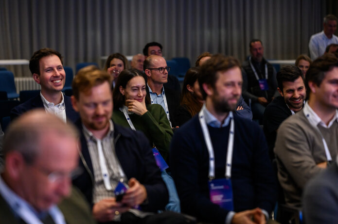 Blick ins Publikum. Mehrere Personen sitzen und hören aufmerksam zu.