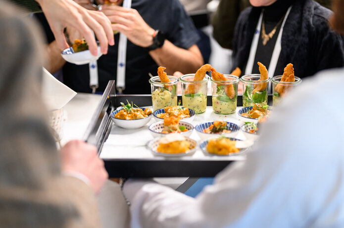 Nahaufnahme von servierten Fingerfood-Gerichten auf einem Tablett, darunter Gläser und kleine Schalen mit Snacks.
